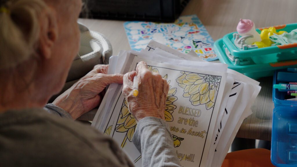 A woman colors in a picture at a skilled nursing facility
